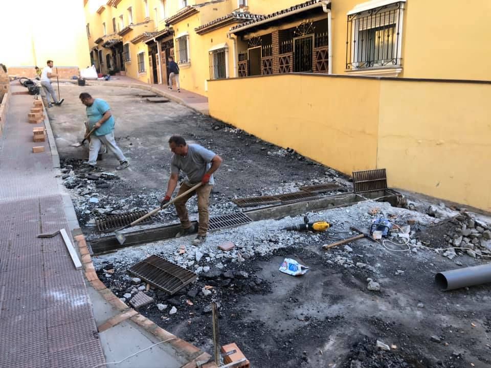 Dos hombres están trabajando en una acera frente a un edificio.