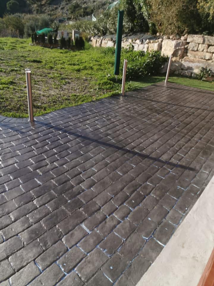 Un camino de entrada de ladrillo con un campo de hierba al fondo