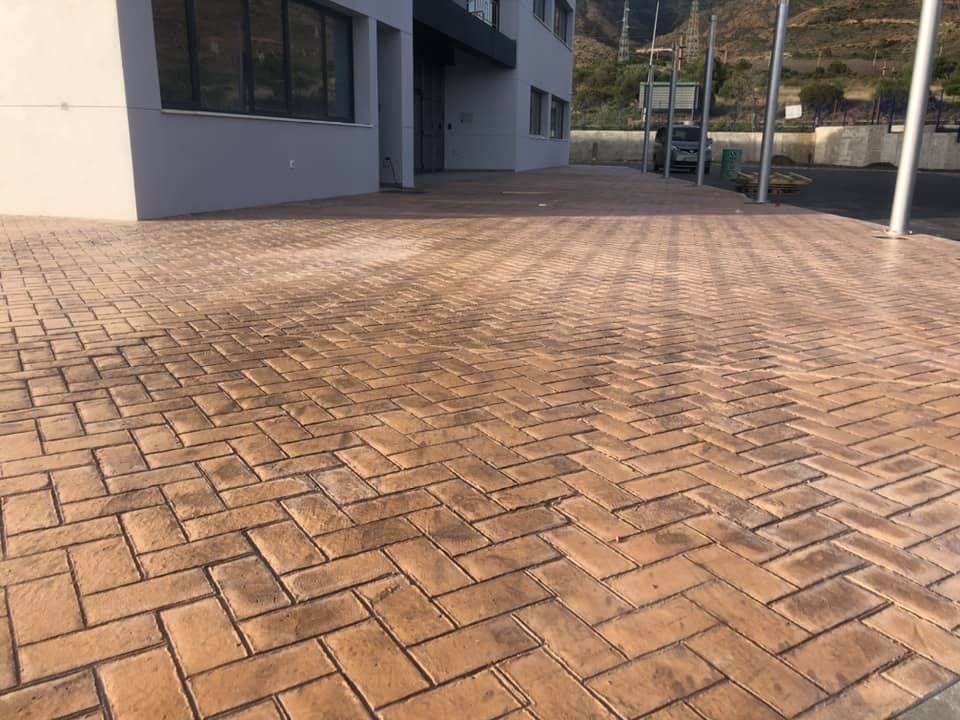 Un camino de entrada de ladrillo con diseño en espiga delante de un edificio.