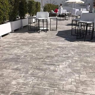 Un patio con mesas, sillas y sombrillas.