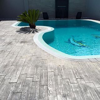 Una gran piscina rodeada de un deck de madera y una palmera.