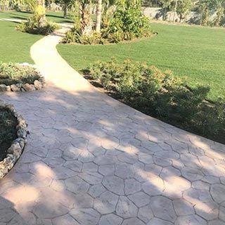 Una pasarela de ladrillos que conduce a un exuberante campo verde.