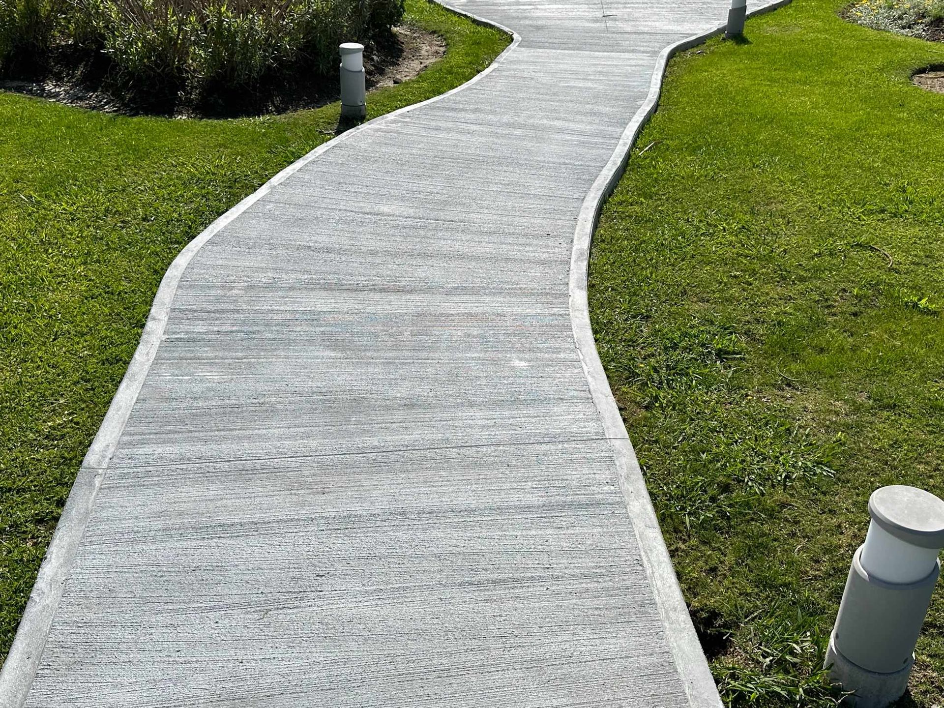 Una pasarela de hormigón que atraviesa un exuberante campo verde.