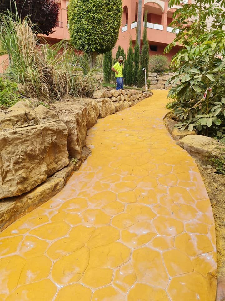 Un hombre está parado en una pasarela amarilla en un jardín.