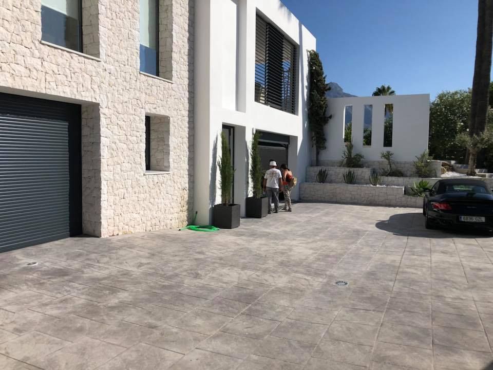 Un coche negro está aparcado delante de un gran edificio blanco.