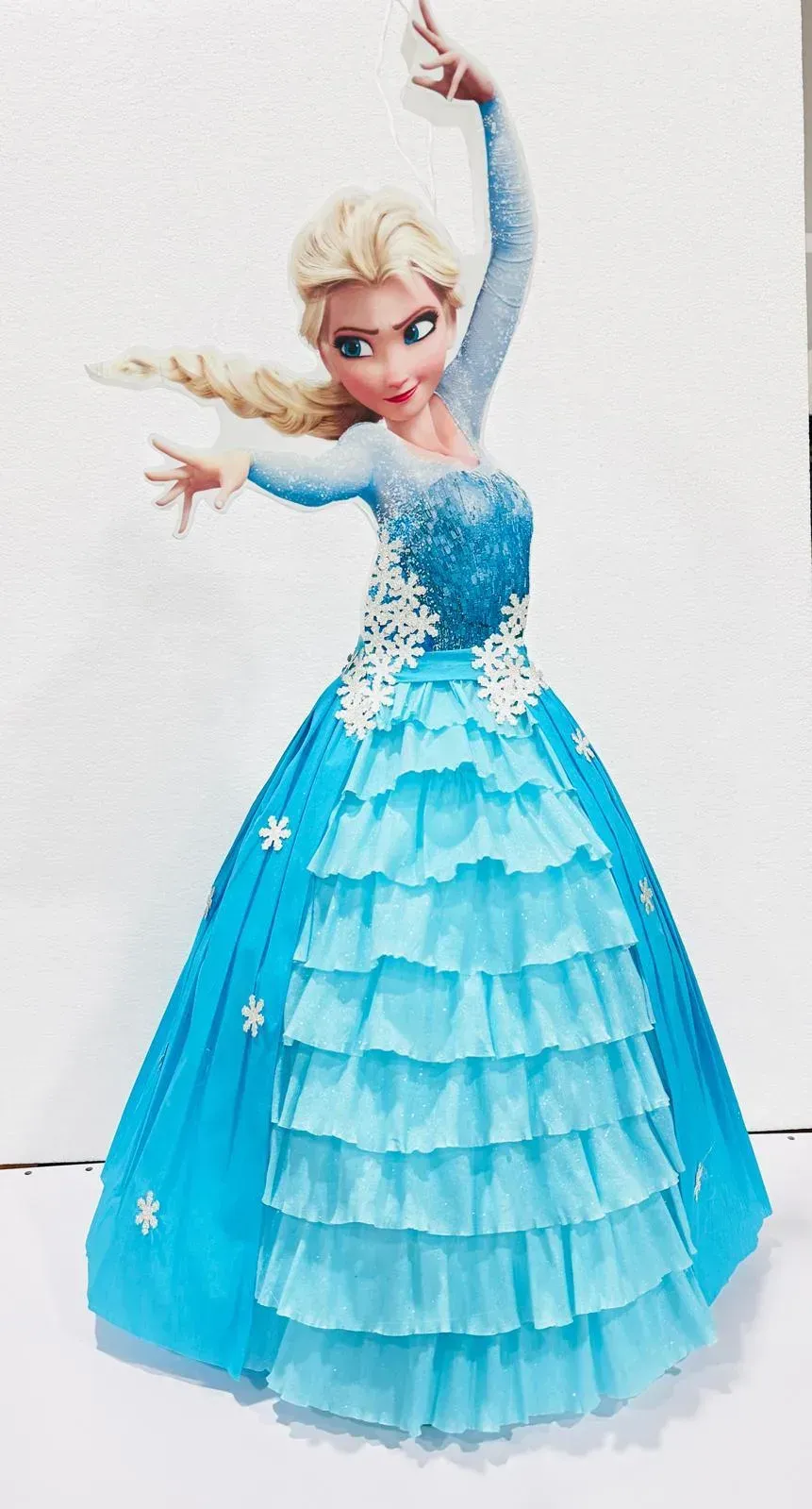 Elsa animada con un vestido azul brillante, posando con un brazo levantado y el otro extendido.