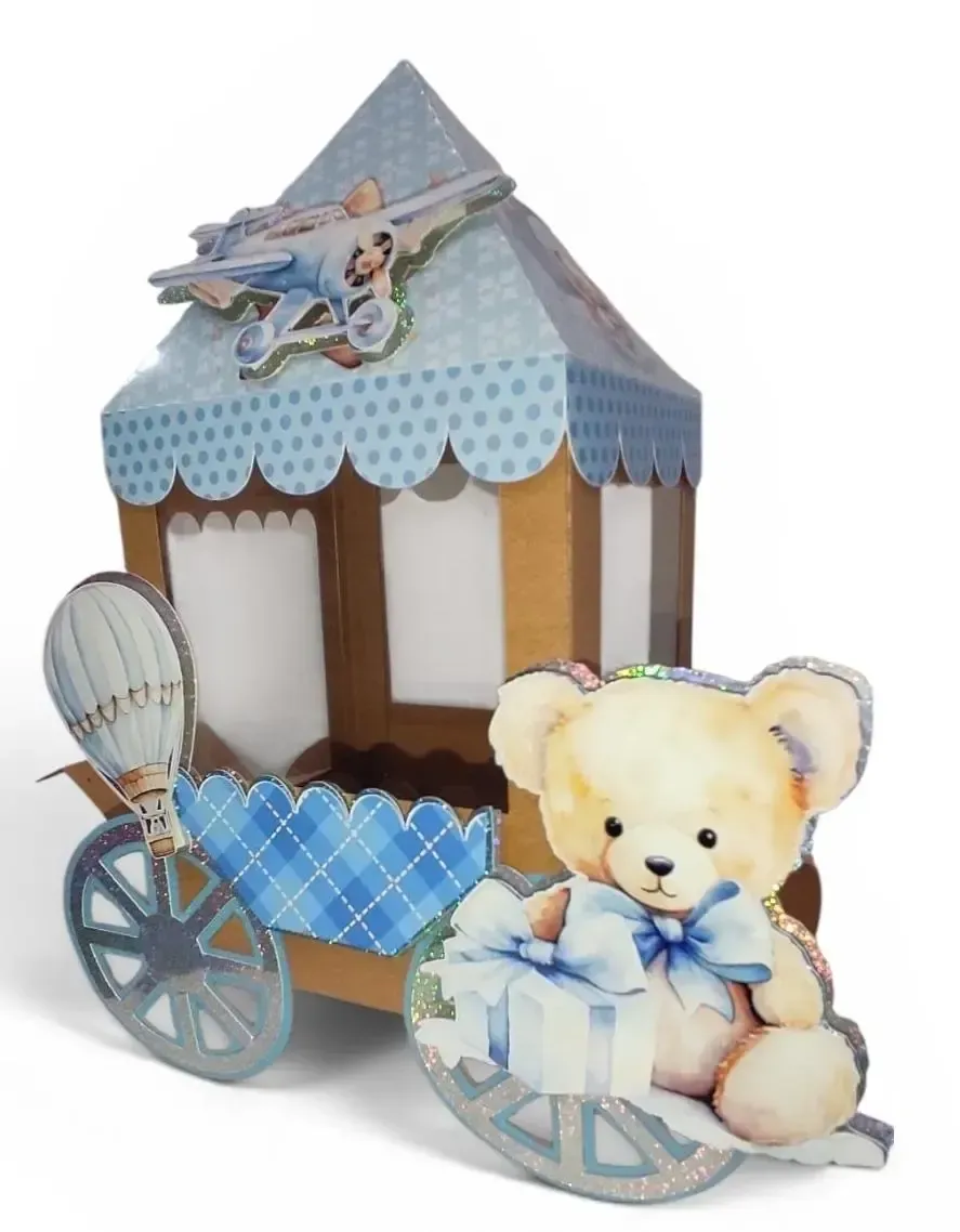 Un osito de peluche con un lazo azul junto a un carrusel de papel decorado en azul y blanco.
