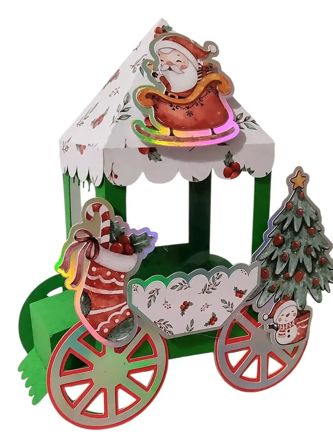 Manualidad de papel con temática navideña de Papá Noel en un trineo y un árbol decorado sobre un cenador verde y rojo con ruedas.
