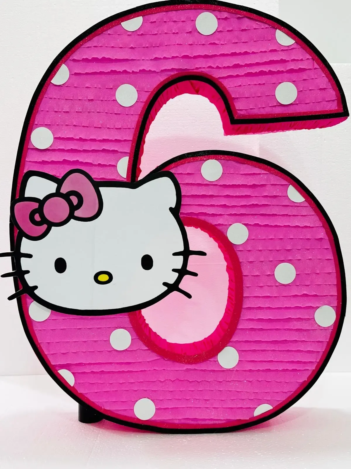Número 6 rosa de lunares con la cara y el lazo de Hello Kitty.