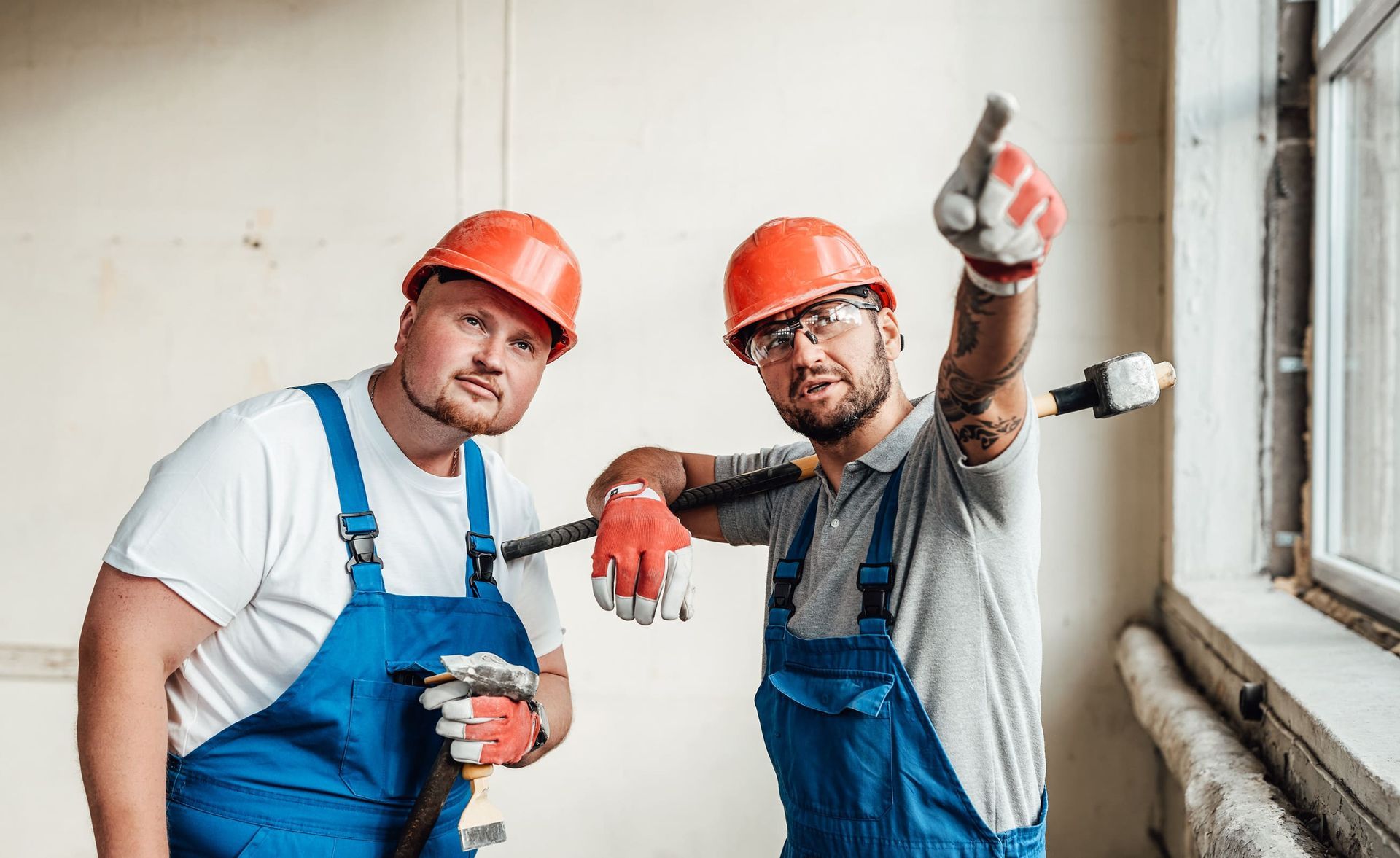Dos trabajadores de la construcción están parados uno al lado del otro en una habitación.
