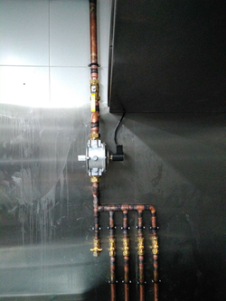 Un primer plano de una tubería de cobre en una pared de acero inoxidable.