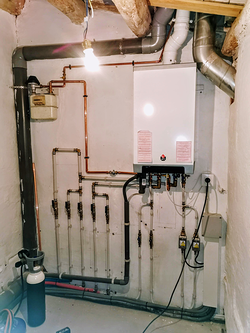 Una habitación con una caldera y tuberías en la pared.