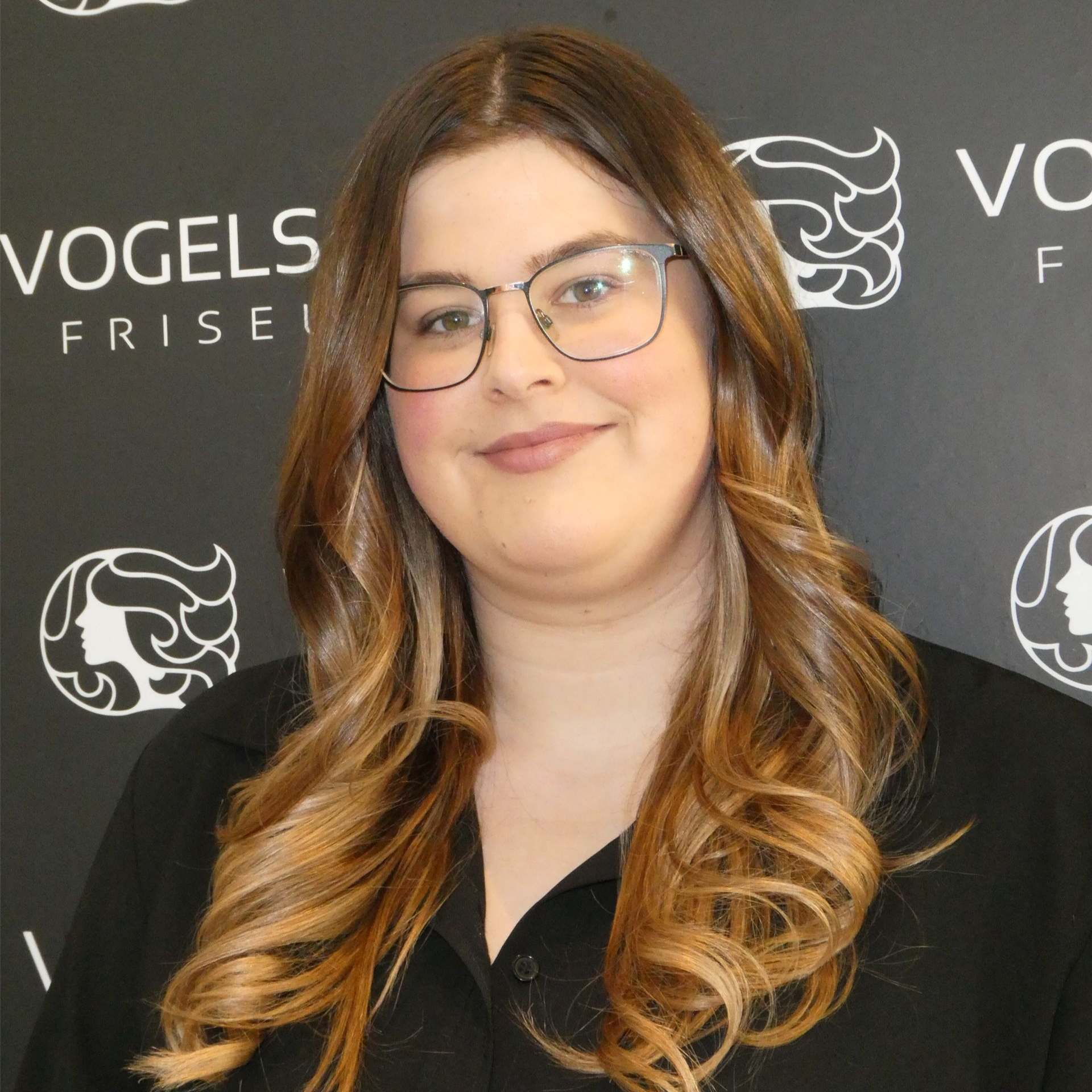 Ein Mann im karierten Hemd lächelt und hat die Arme verschränkt.