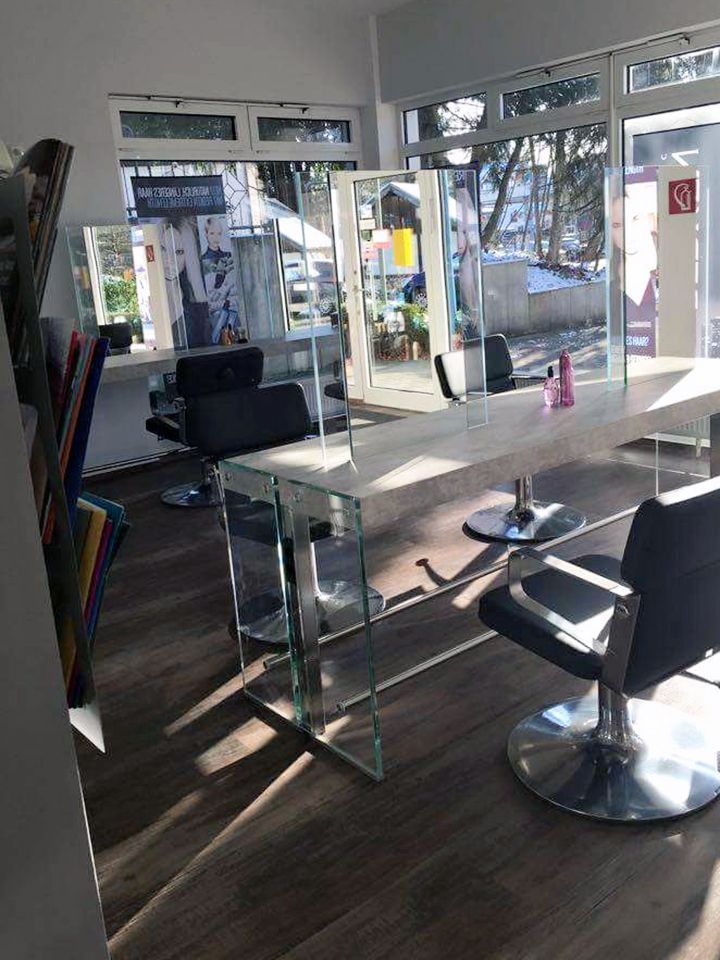 Ein Friseursalon mit einem Tisch und Stühlen vor einem großen Fenster.