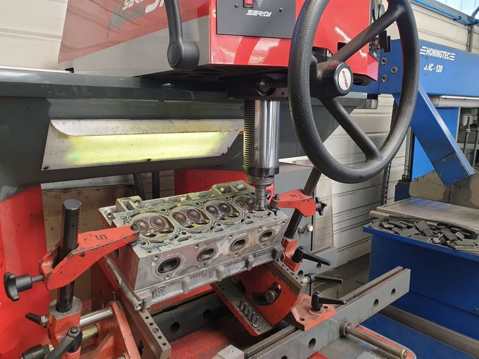 Réparation de la culasse d'un moteur par une machine dans un atelier.