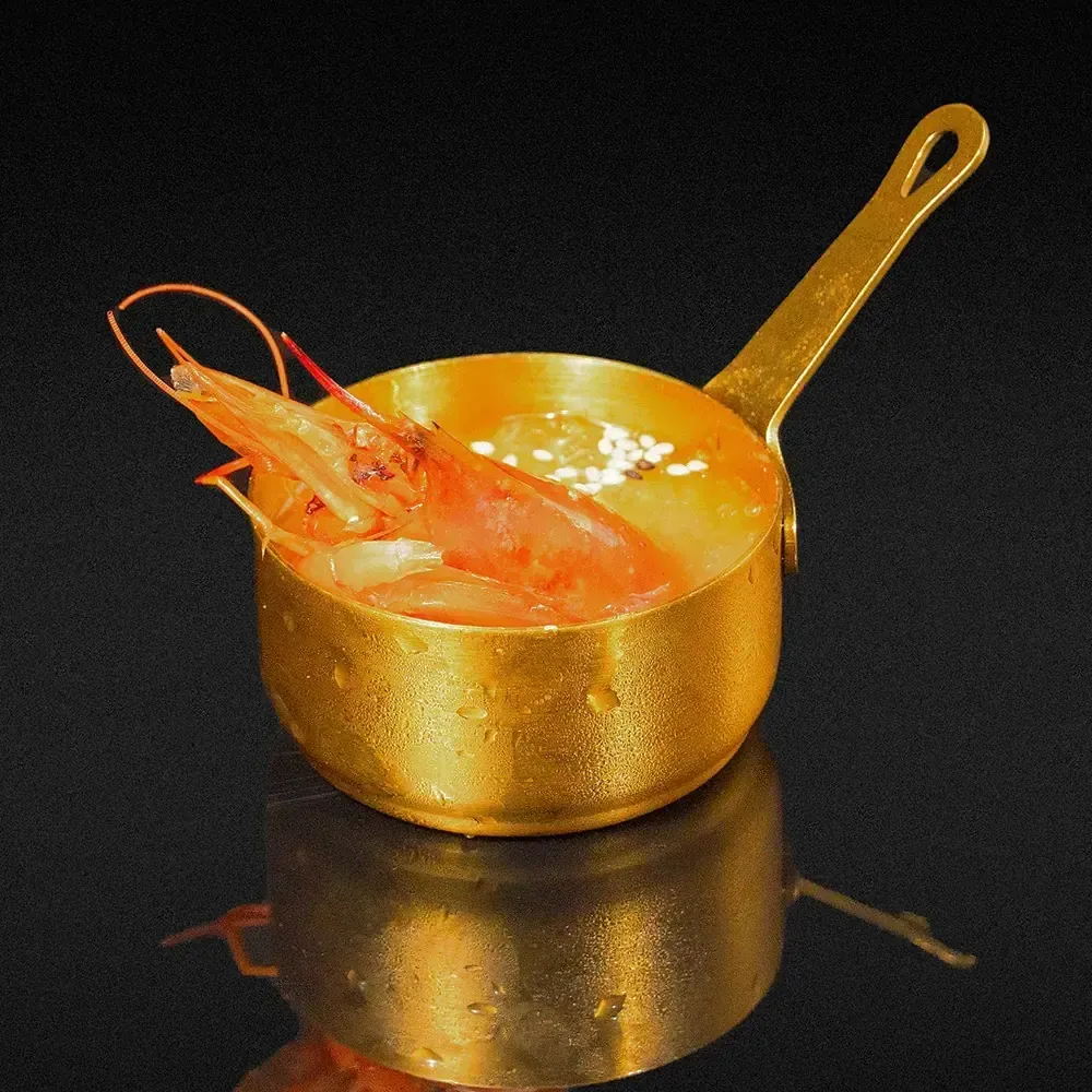 Rollos de sushi cubiertos con caviar negro y wasabi verde en un plato rectangular blanco.