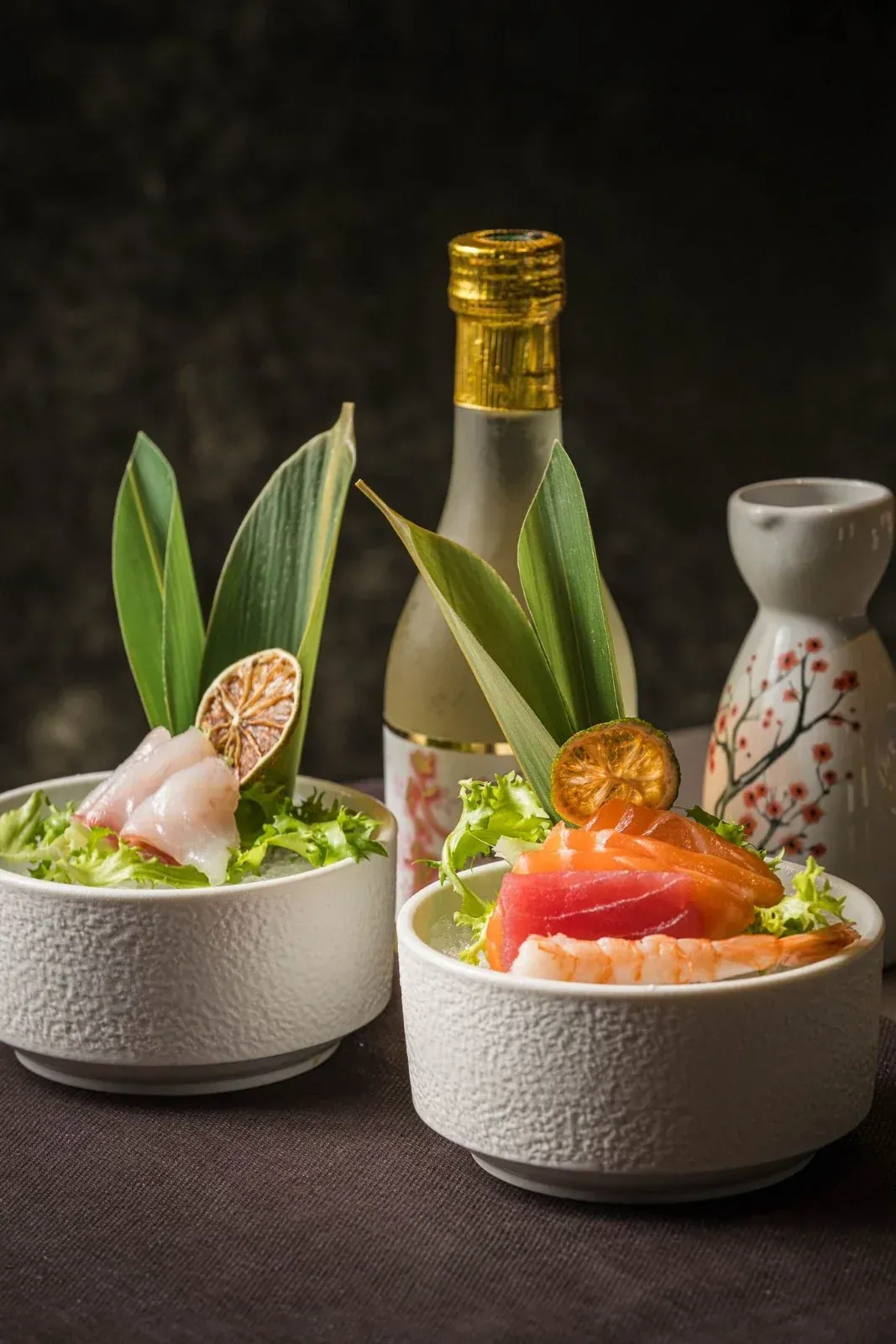 Plato de sushi con hielo seco, sobre una mesa de restaurante con otros platos.