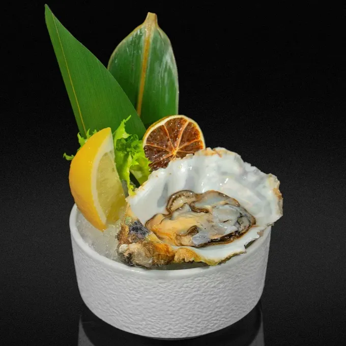 Sashimi de salmón en hielo en un pequeño recipiente azul, sobre una mesa marrón.