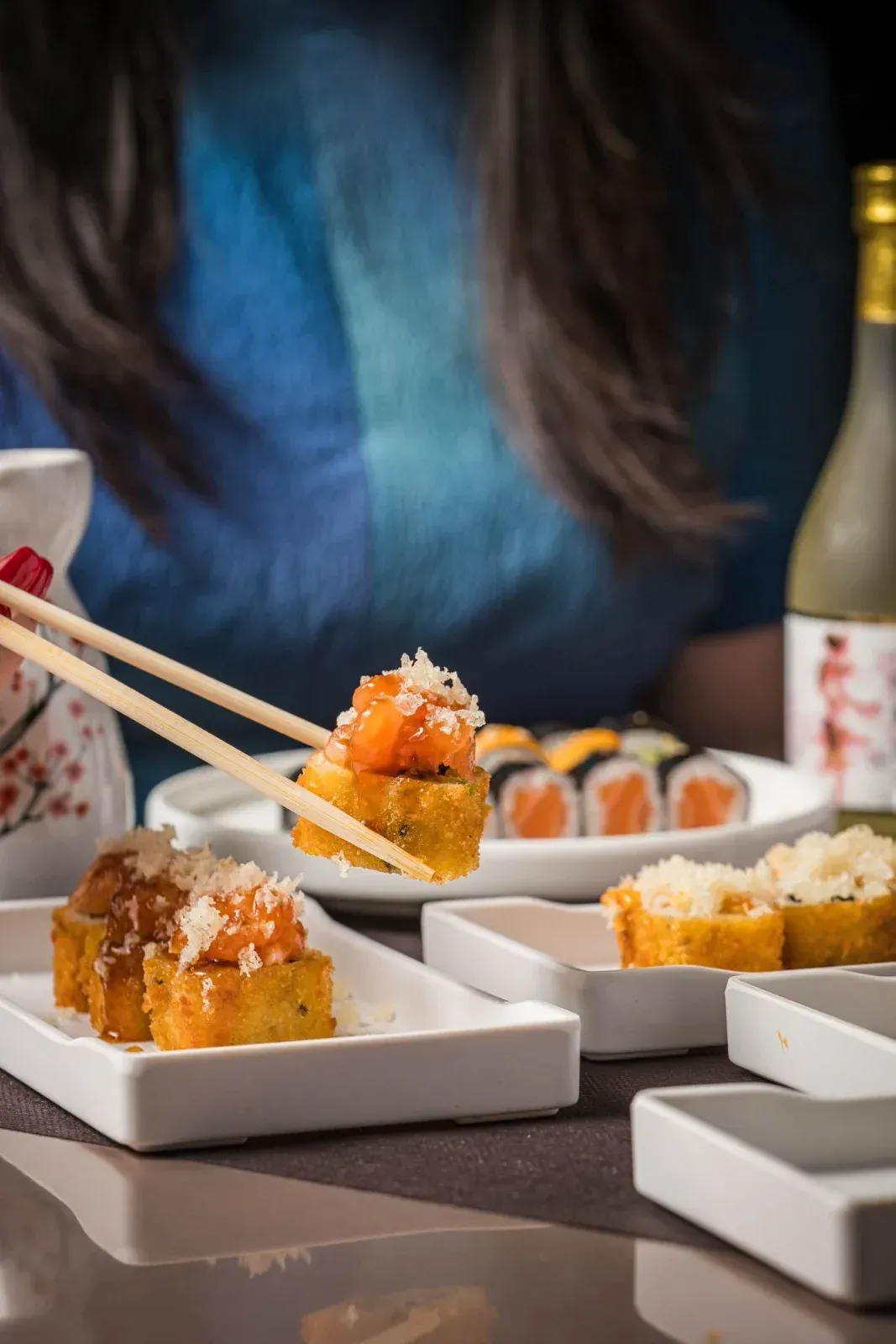 Plato de sushi con hielo seco, sobre una mesa de restaurante con otros platos.