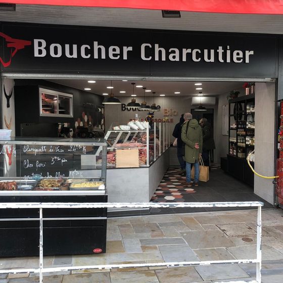Façade de boucherie avec auvent rouge et comptoir d'exposition