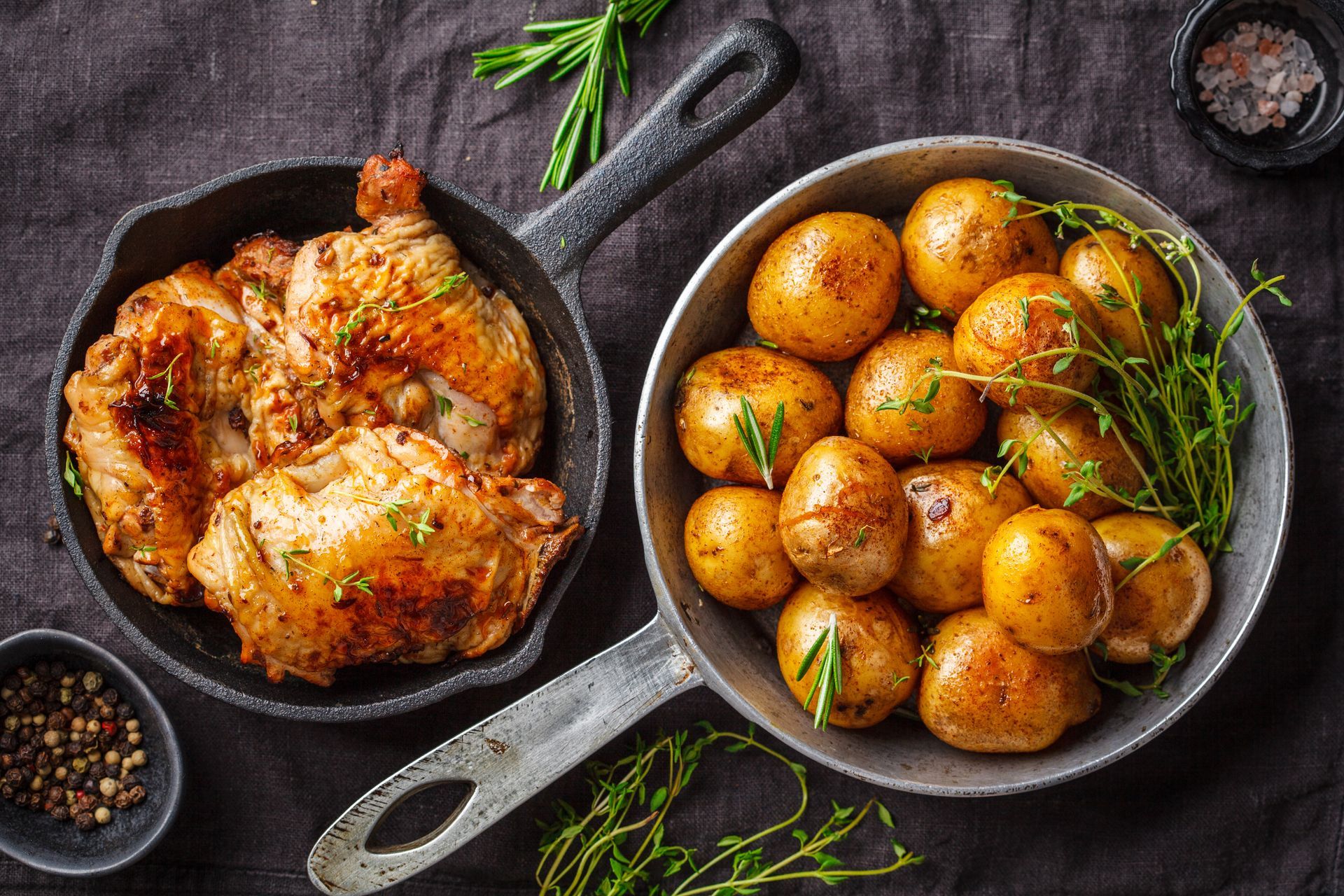Poulet poêlé et une poêlée de pommes de terre nouvelles rôties garnies d'herbes sur une table sombre