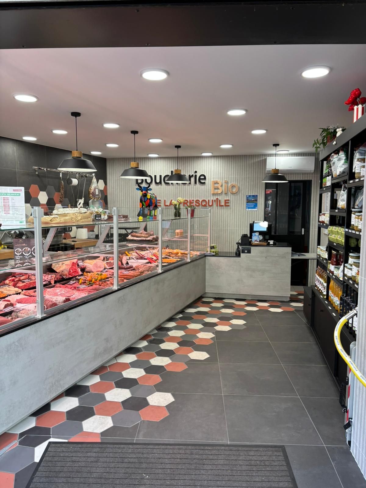 Intérieur lumineux de la boulangerie avec vitrine à pâtisseries, sol carrelé et coin repas au comptoir.