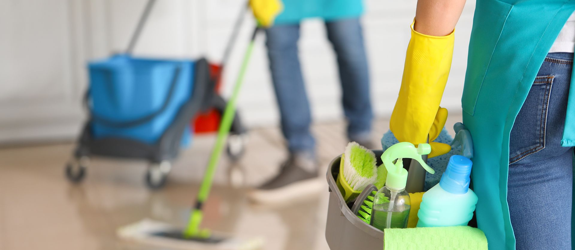 Une personne tient les produits de nettoyage, une autre lave le sol.