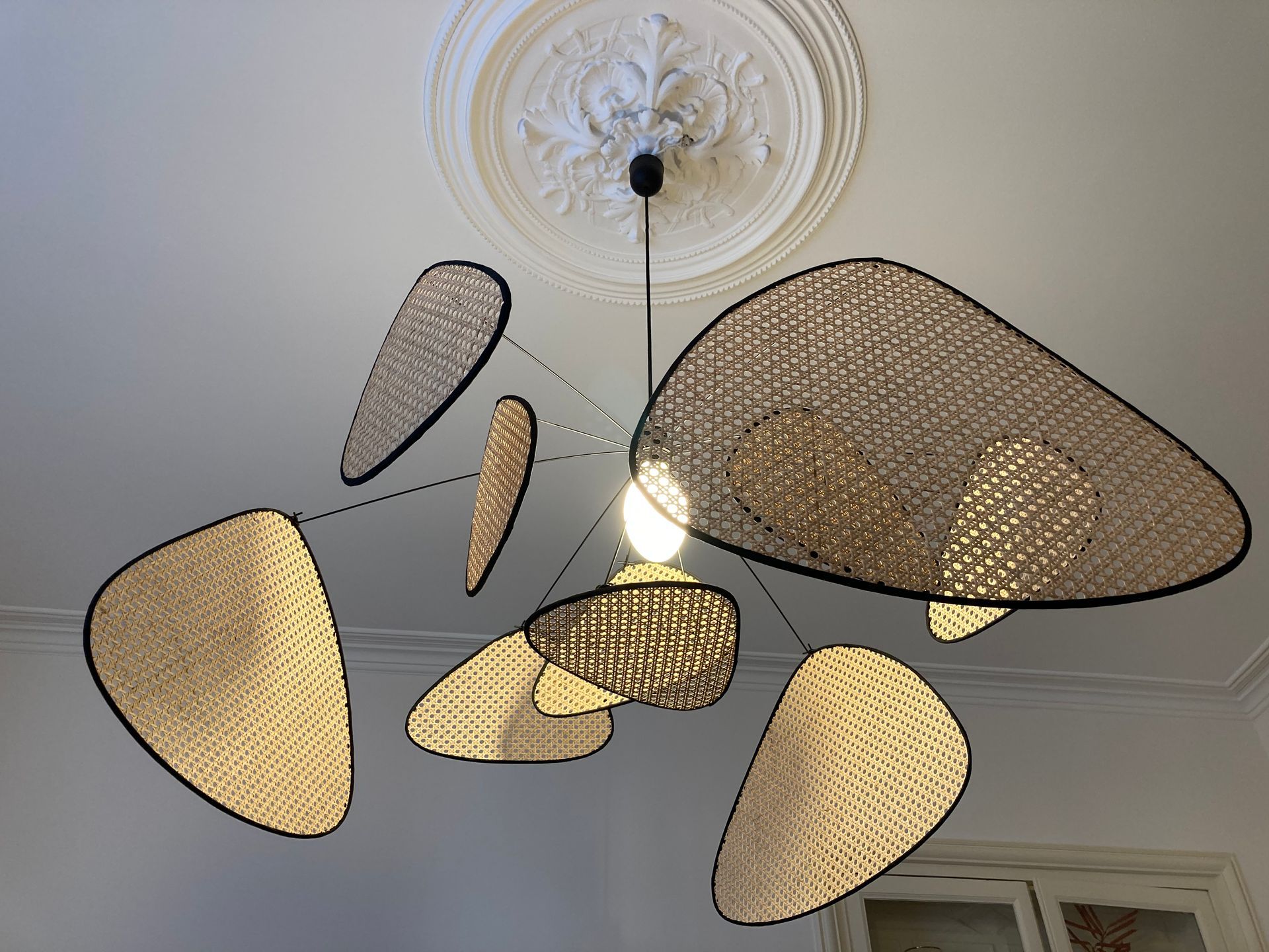 Suspension en osier beige et noir accroché à une belle moulure au plafond