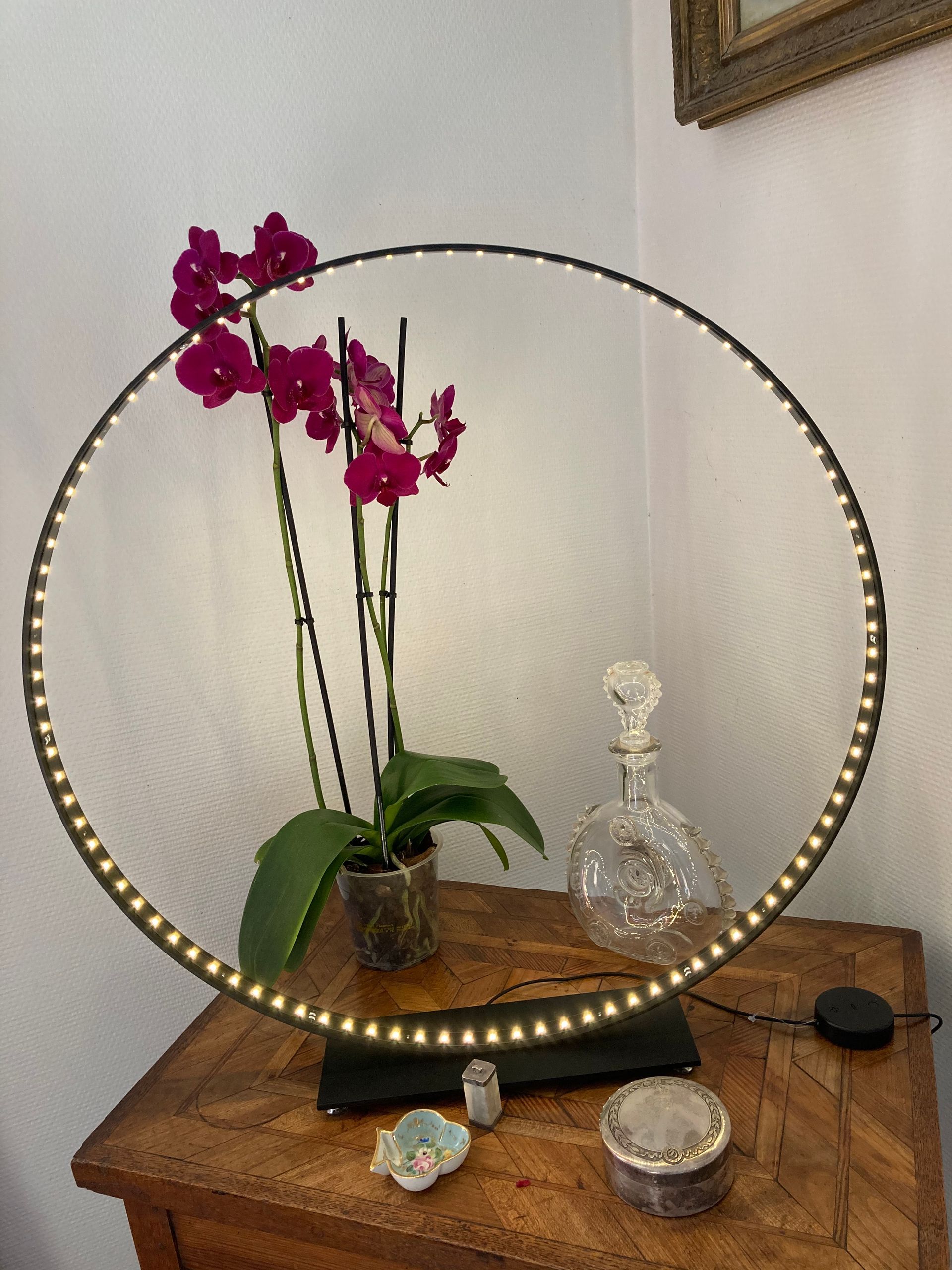 Orchidée à côté d'une belle bouteille en verre derrière une lampe en forme de cercle