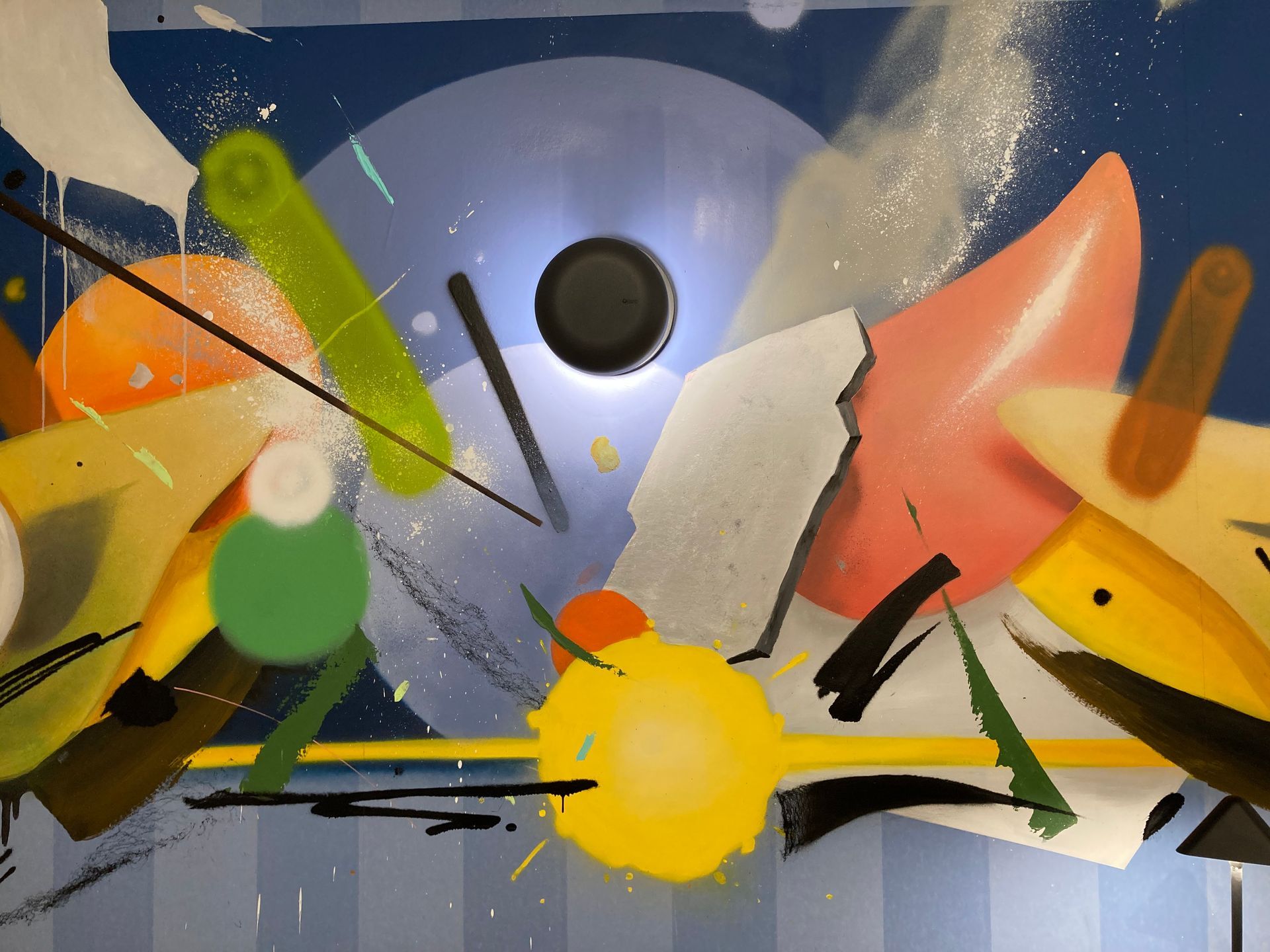 Mur avec des graffitis ayant une applique murale ronde et noire dessus