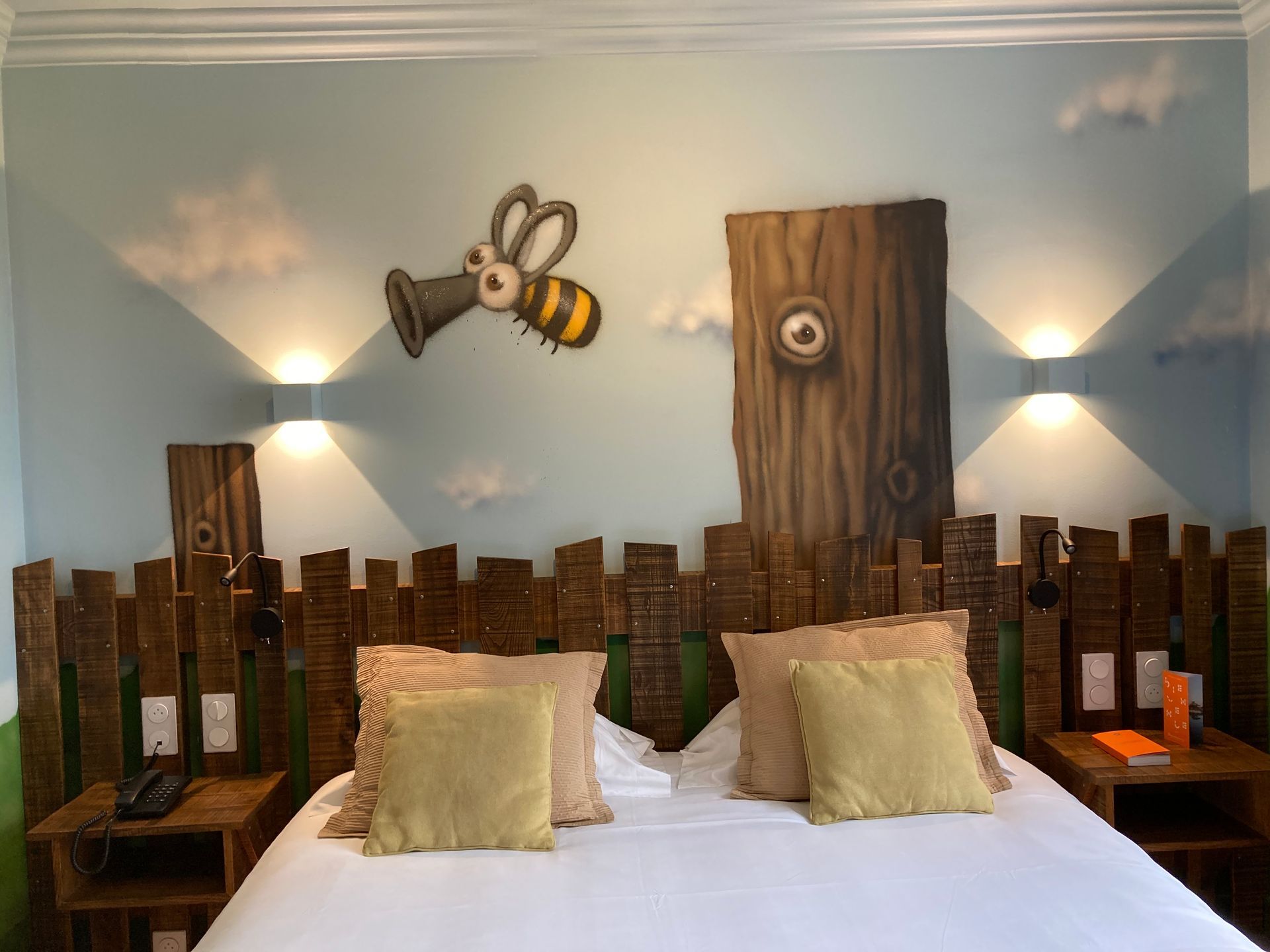 Mur d'une chambre avec une fresque représentant une abeille et un tronc d'arbre et deux appliques murales