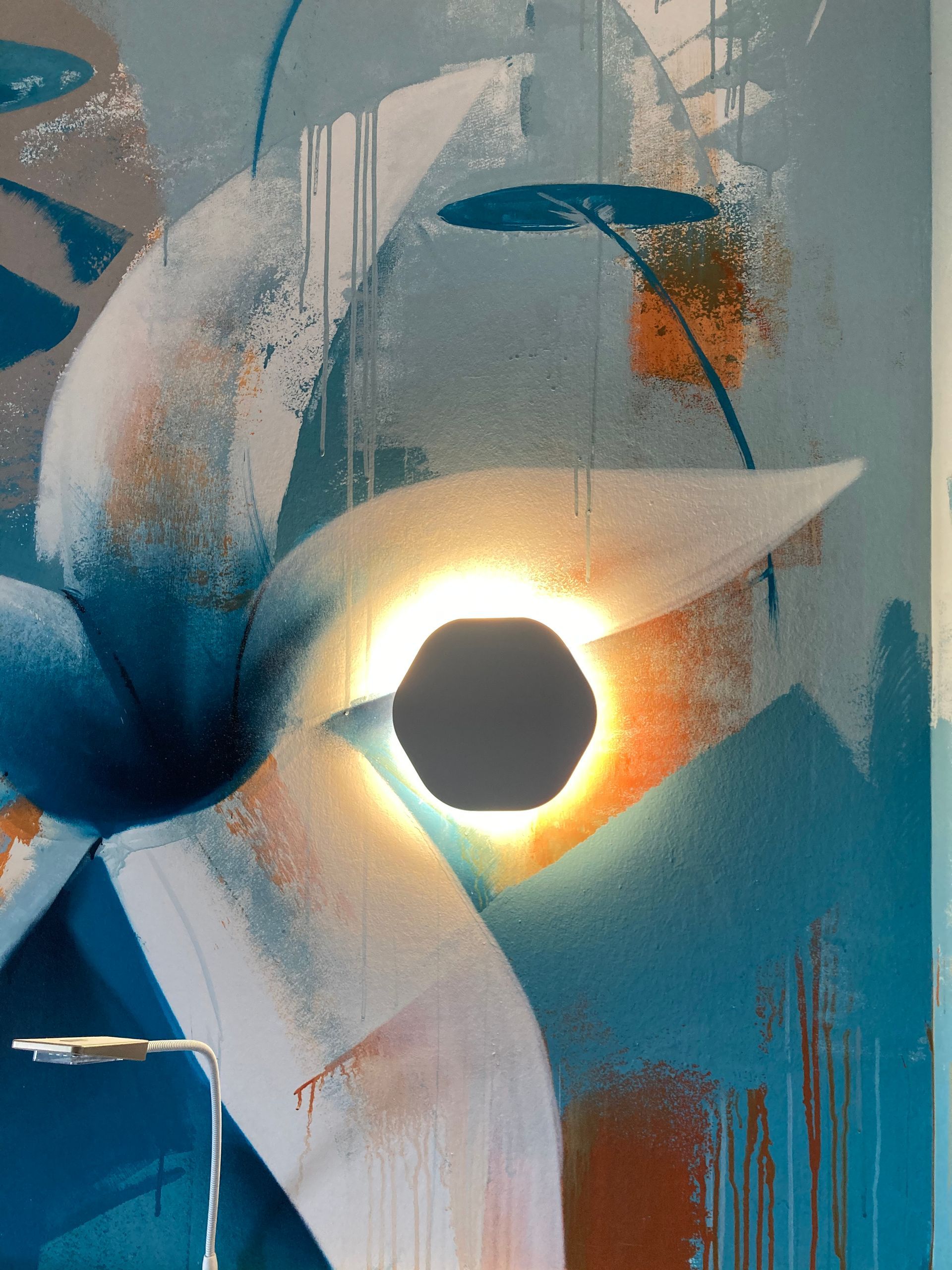 Grosse fleur peinte sur un mur avec une applique allumée à côté