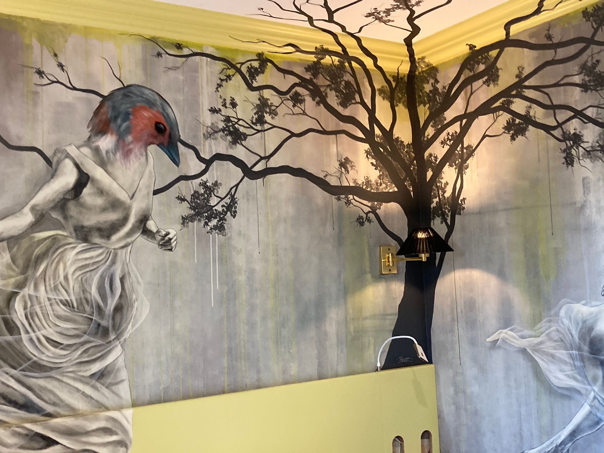 Arbre peint dans l'angle d'une pièce avec un oiseau ayant un corps de femme peint également