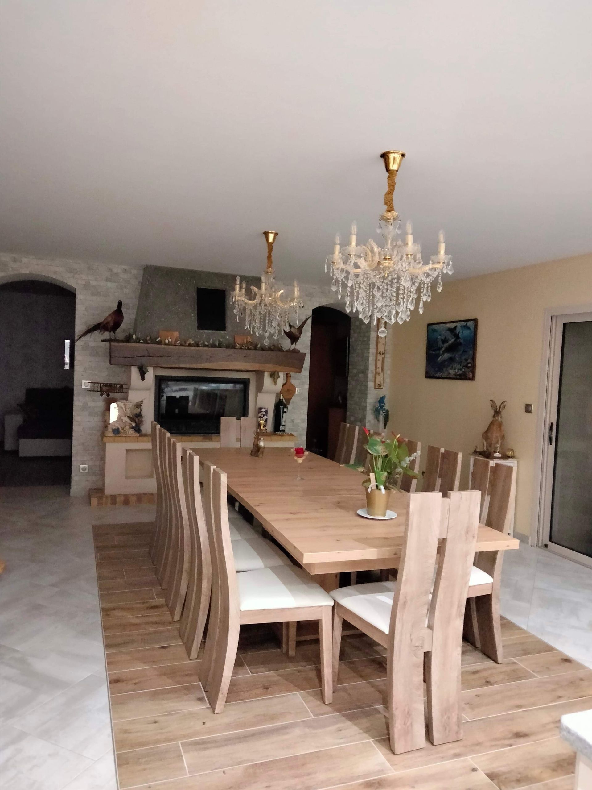 Cheminée au fond d'une salle à manger ayant deux lustres au style ancien