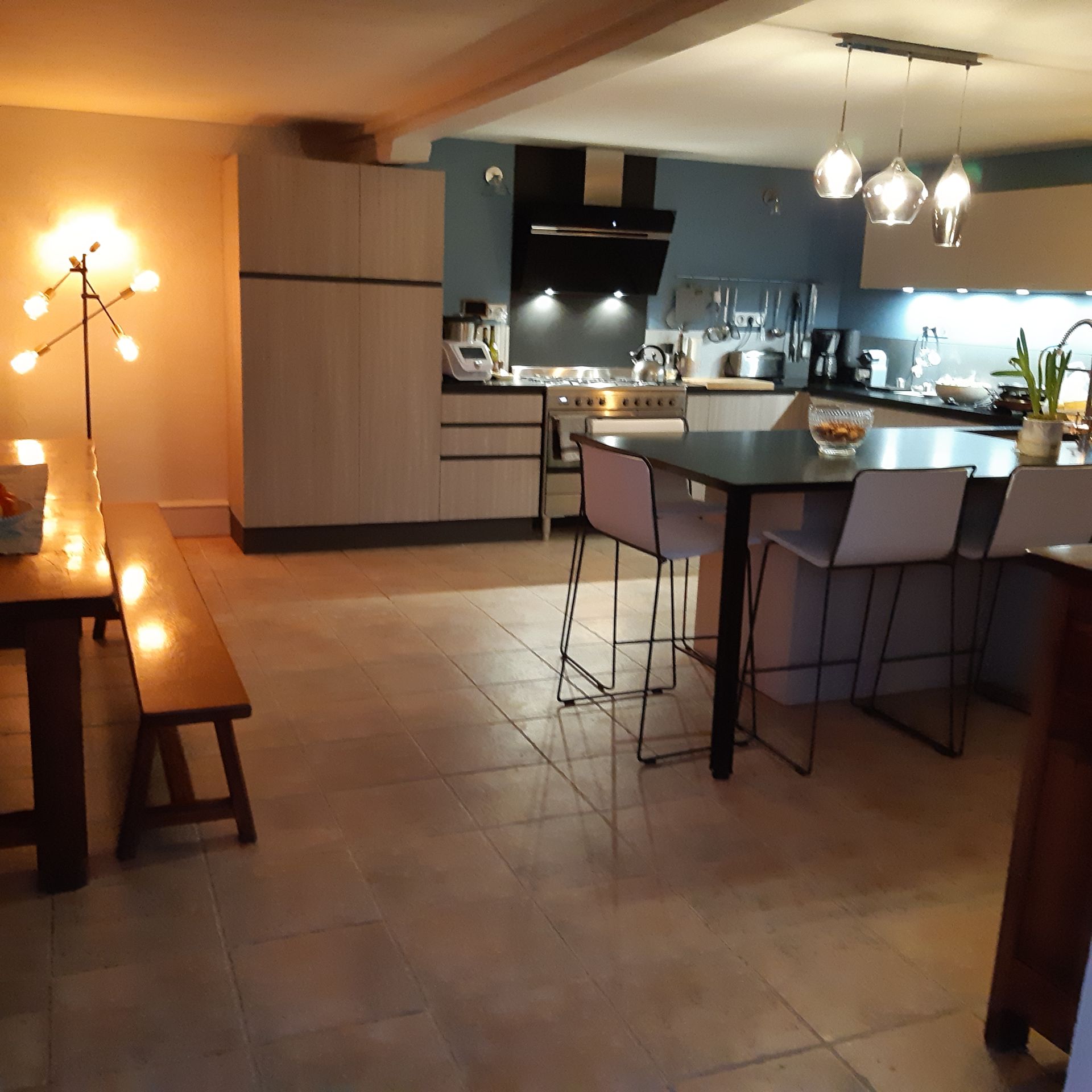 Cuisine éclairée par des ampoules aux tons froids et salle à manger à côté éclairée par des tons chauds