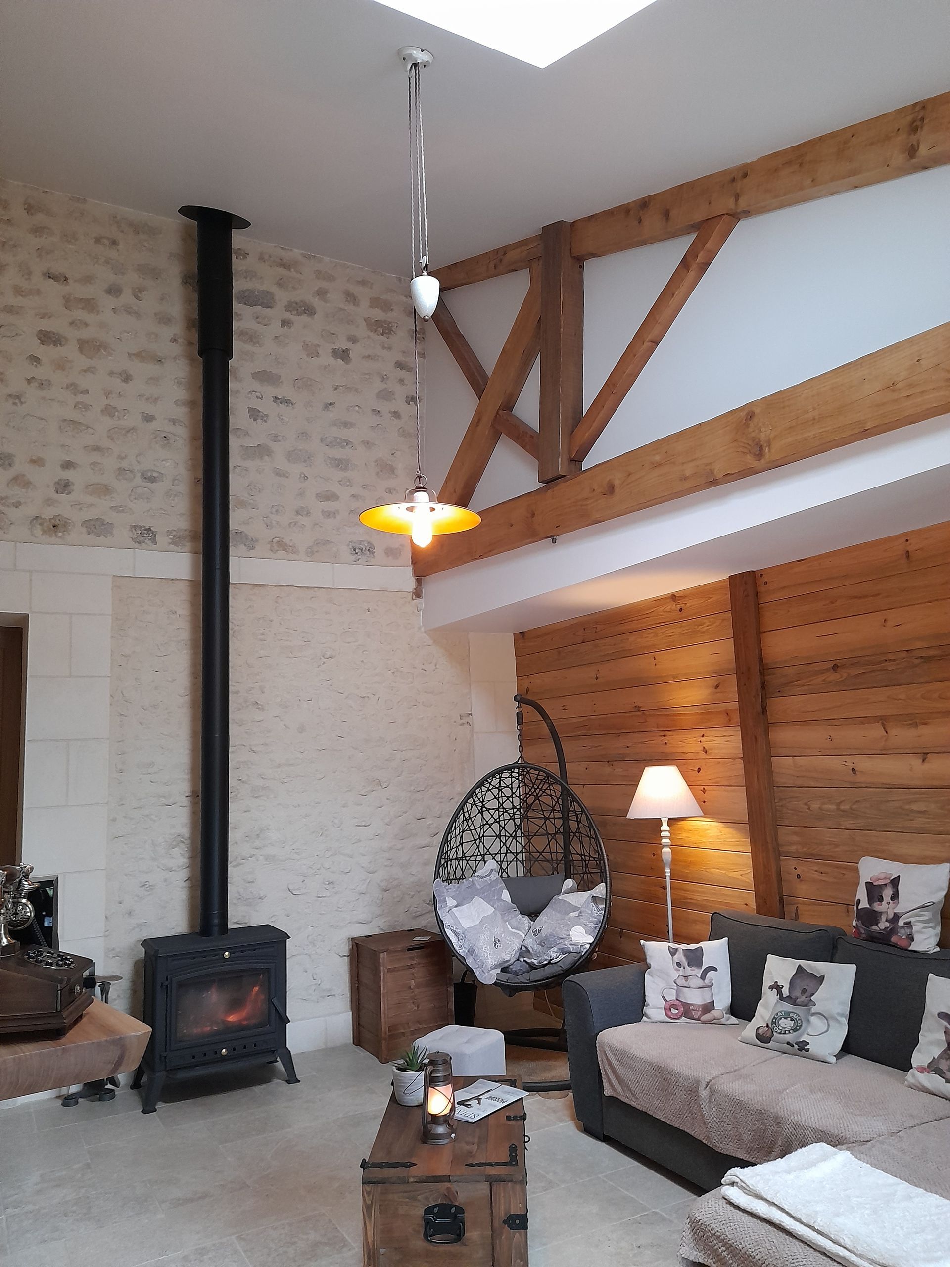 Fauteuil en œuf suspendu dans une pièce en pierres apparentes et bois