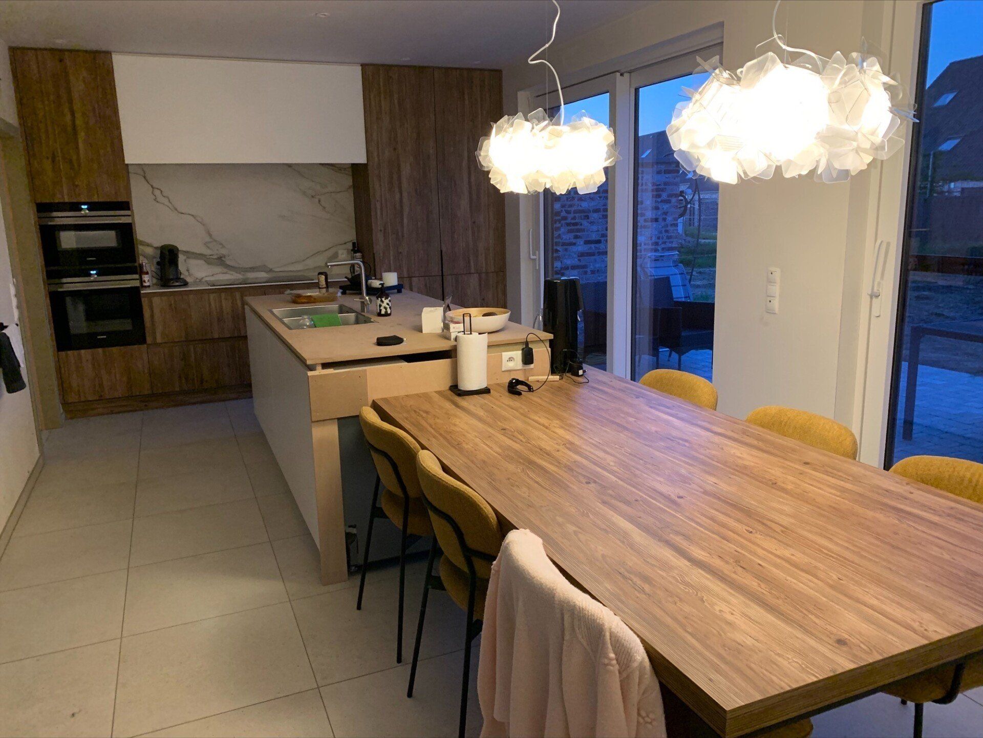 Deux lustres ressemblant à des nuages au-dessus d'un îlot de cuisine et d'une table