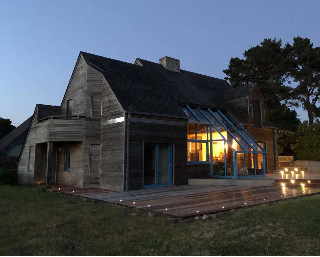 Maison avec une véranda et une terrasse aux contours éclairée par des spots au sol