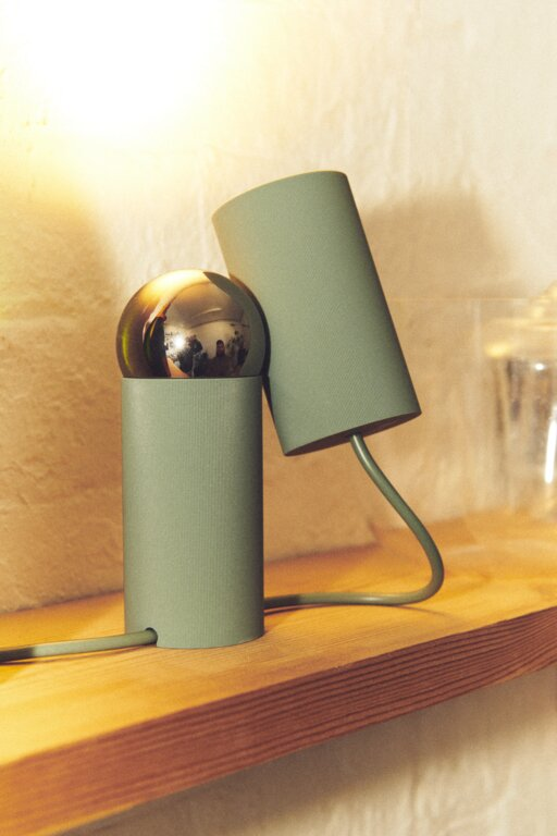 Lampe verte devant un mur en crépi jaune