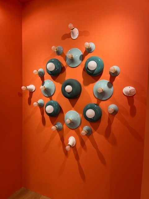 Trois appliques murales design sur un mur orange