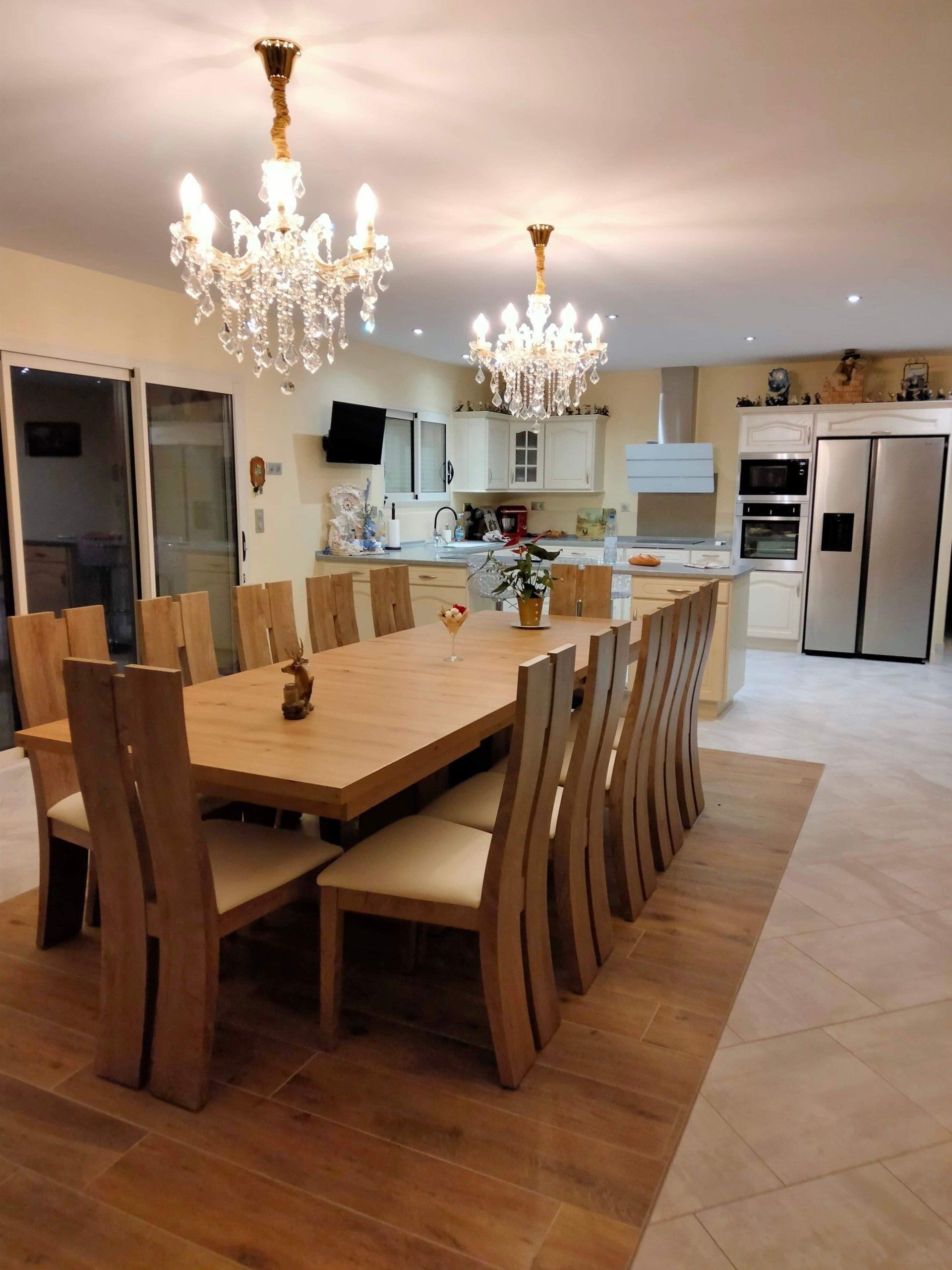 Immense table de salle à manger en bois avec des chaises autour de d'anciens lustres au-dessus