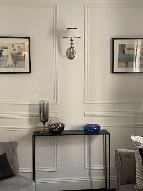 Mur avec des moulures et une petite desserte avec des objets décoratifs dessus