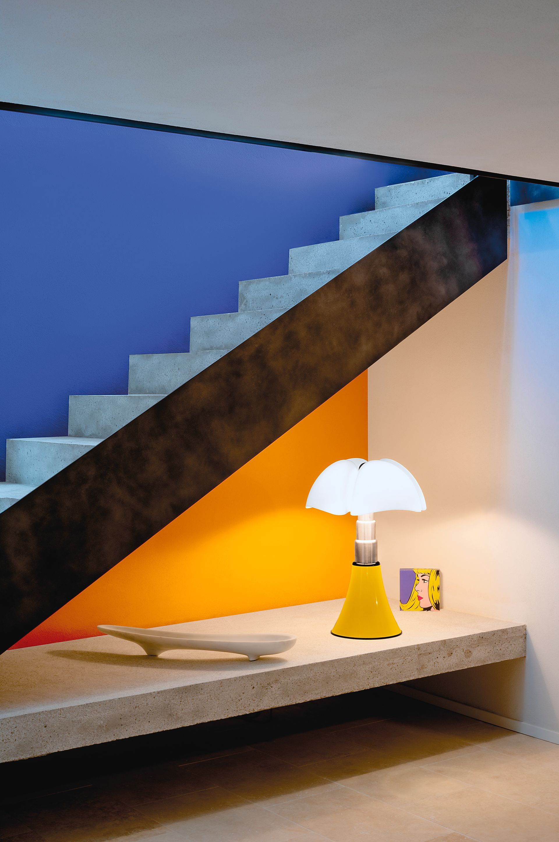 Escalier sur un mur bleu et orange avec une lampe en dessous
