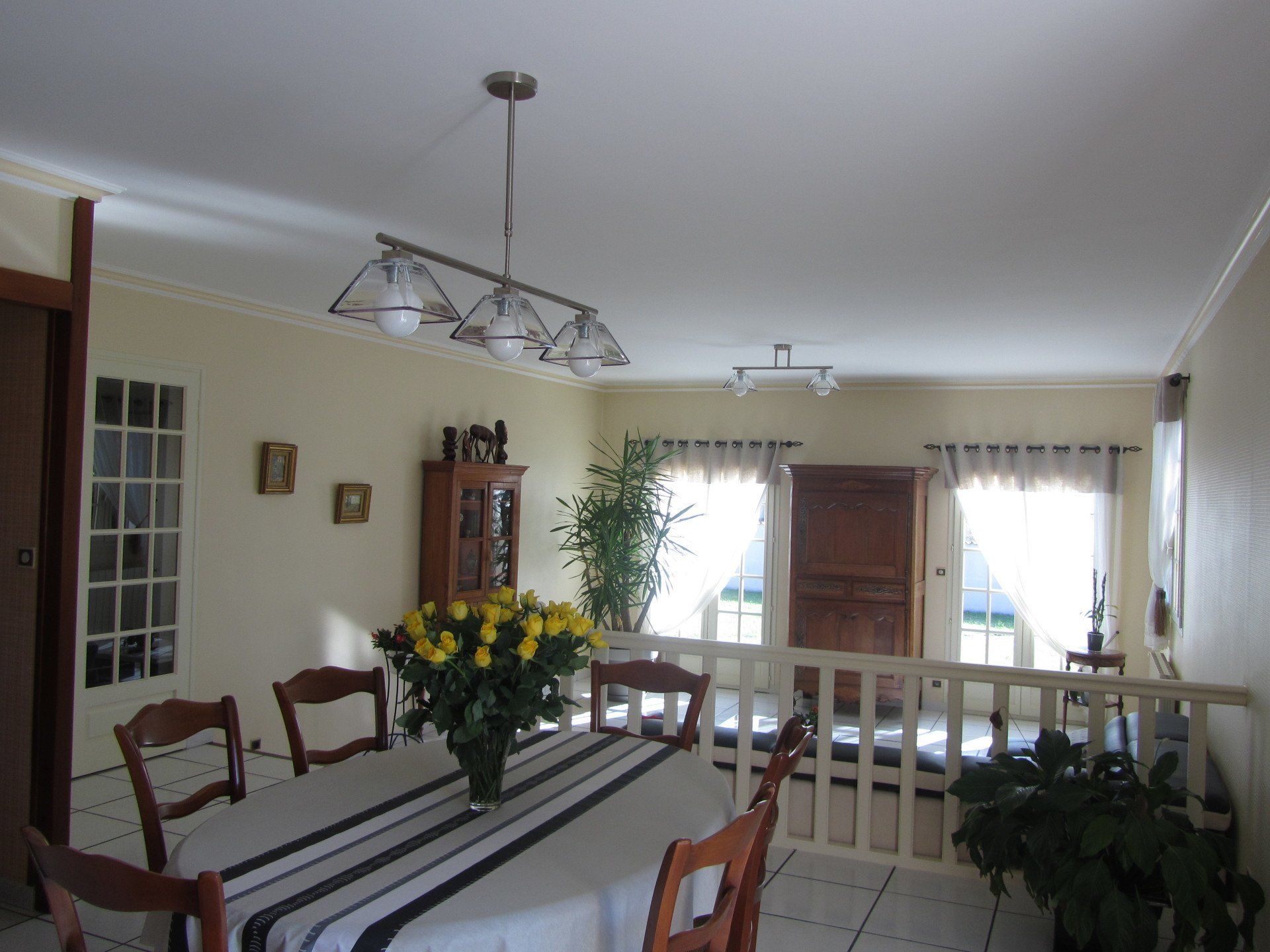 Bouquet de roses jaunes sur une table de salle à manger avec un plafonnier à trois ampoules au-dessus