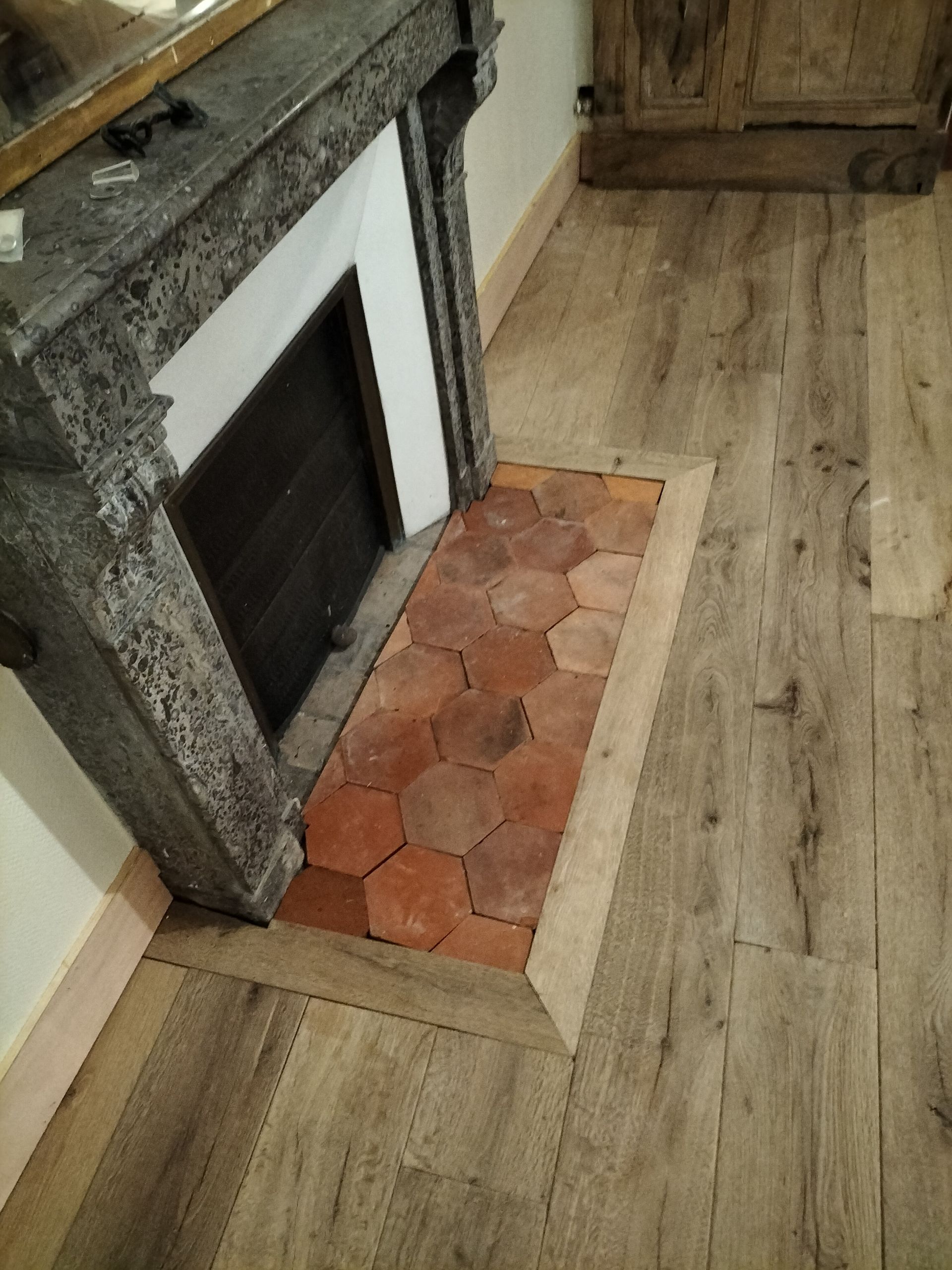 Cheminée avec carreaux hexagonaux en terre cuite et parquet.
