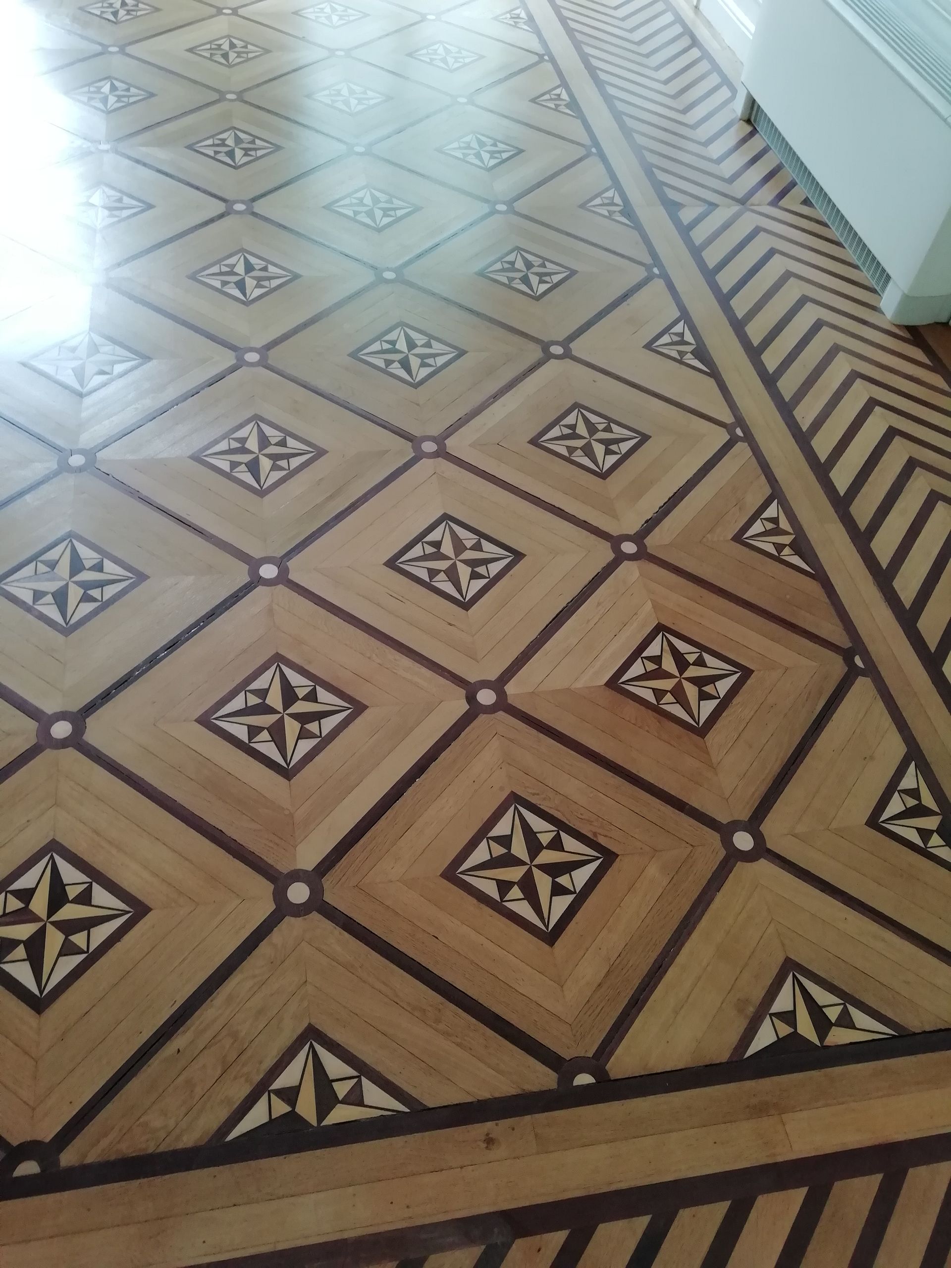 Motif complexe de parquet en bois orné de formes géométriques et de motifs d'étoiles incrustées.
