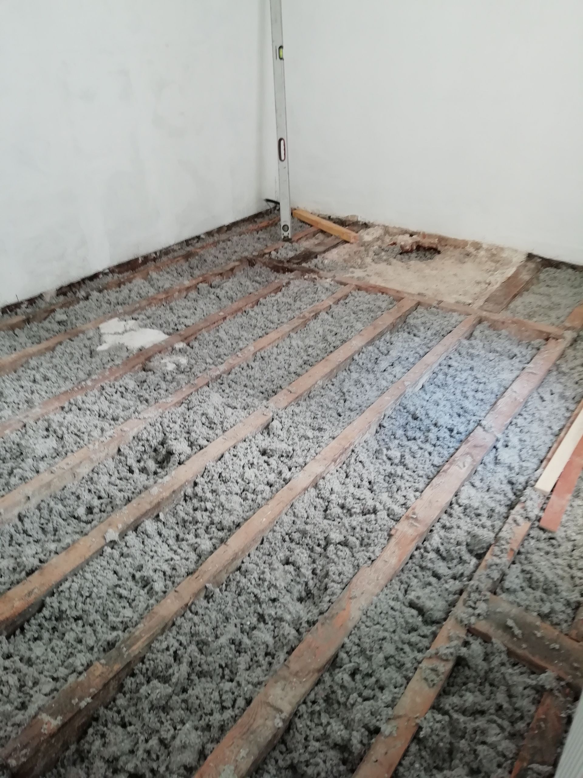 Pièce avec solives et isolation apparentes. Murs blancs, intérieur.