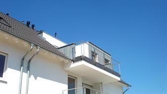 Ein weißes Haus mit Balkon und einem blauen Himmel im Hintergrund.