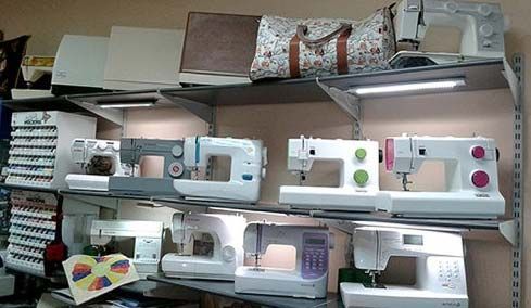 Varias máquinas de coser están alineadas en los estantes de una tienda.