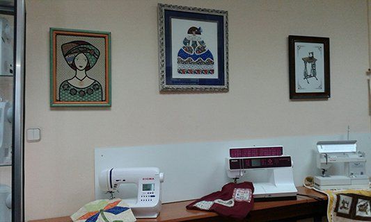 Una máquina de coser está sobre una mesa en una habitación con cuadros en la pared.